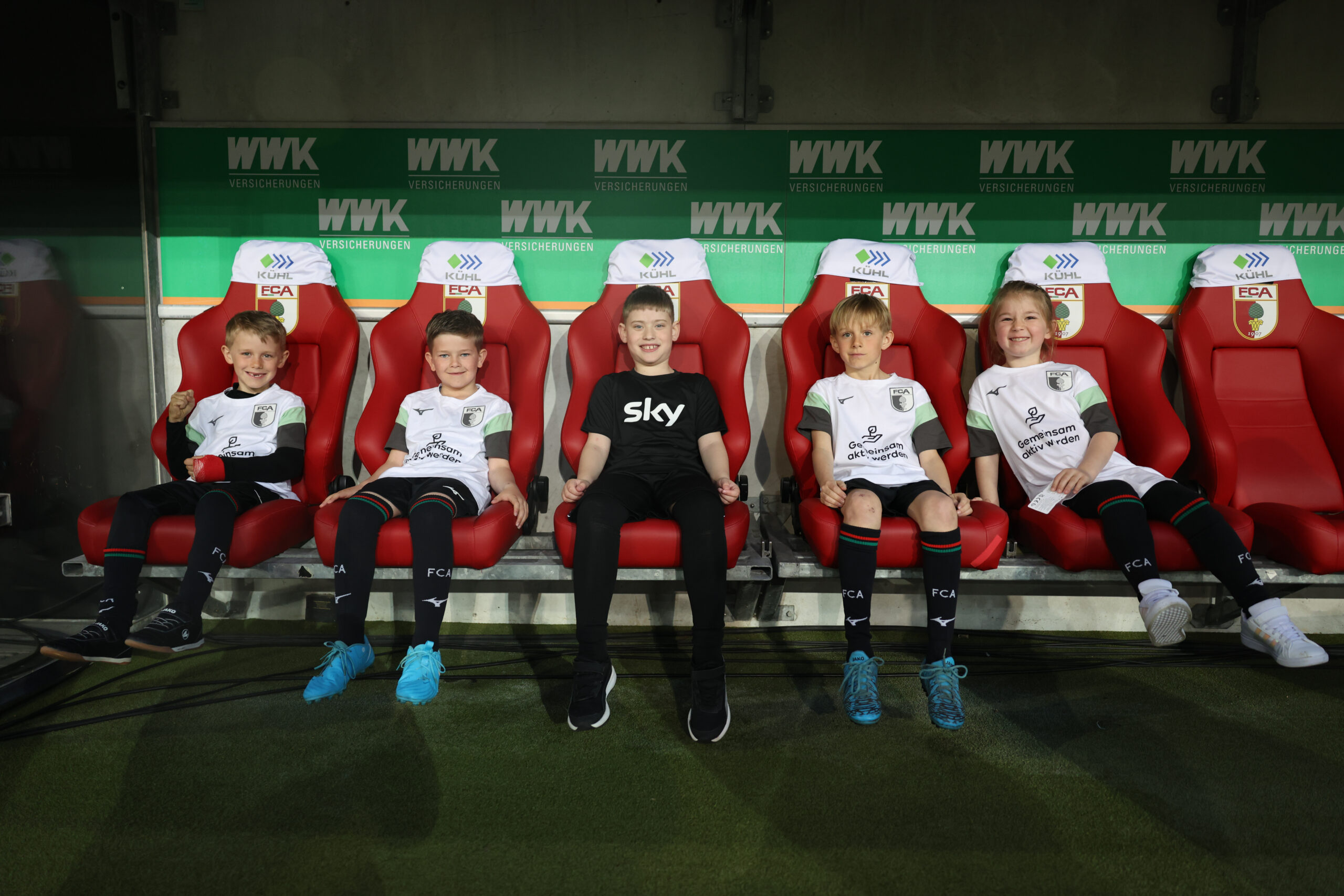 Kinder auf der Spielerbank im Stadion des FC Augsburg