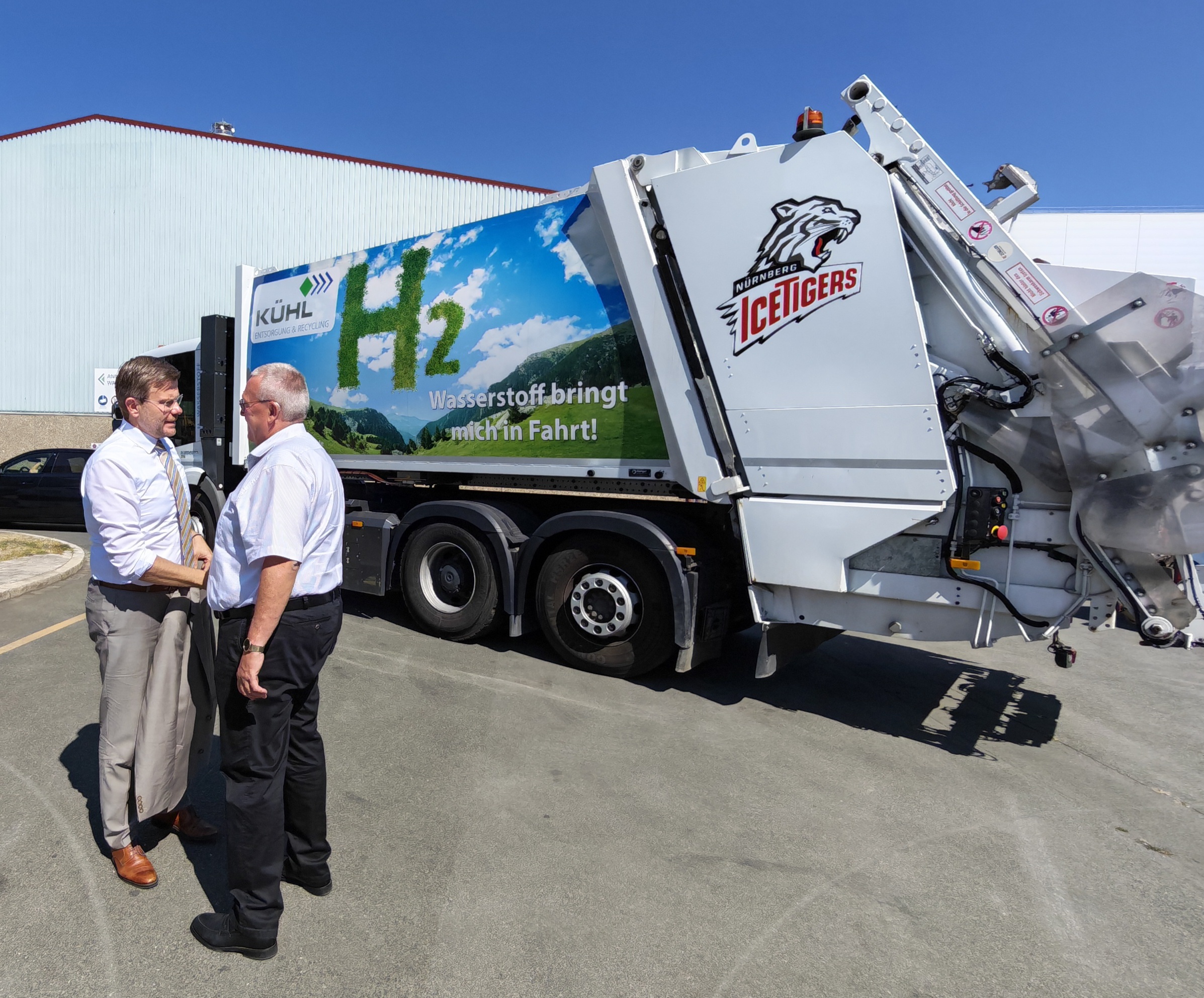 Gespräch vor einem Kühl-Sammelfahrzeug mit H2-Aufdruck in Nürnberg