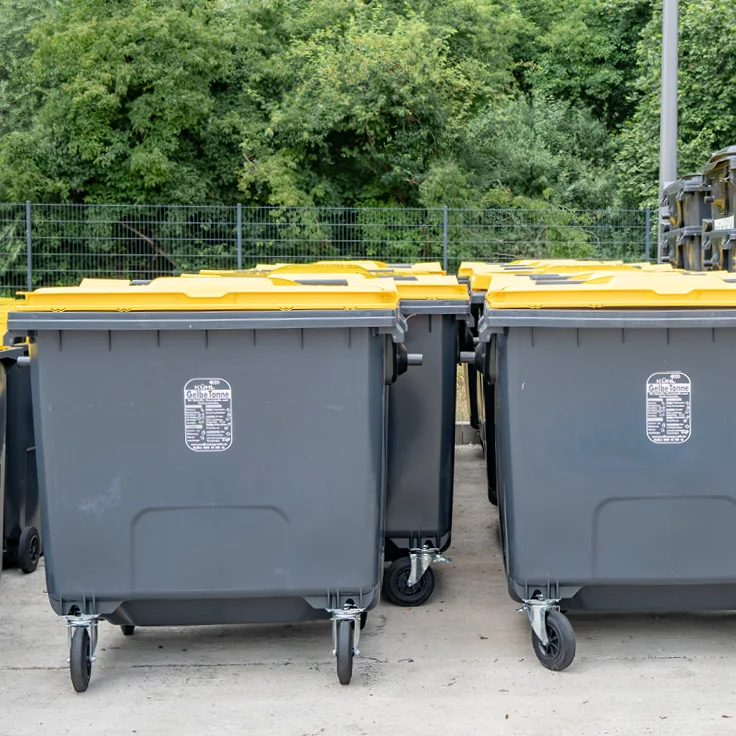 Graue Umleerbehälter mit gelben Deckeln in einer Reihe